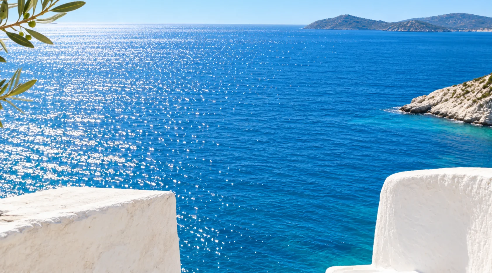 Sunlit Aegean sea seen between whitewashed walls